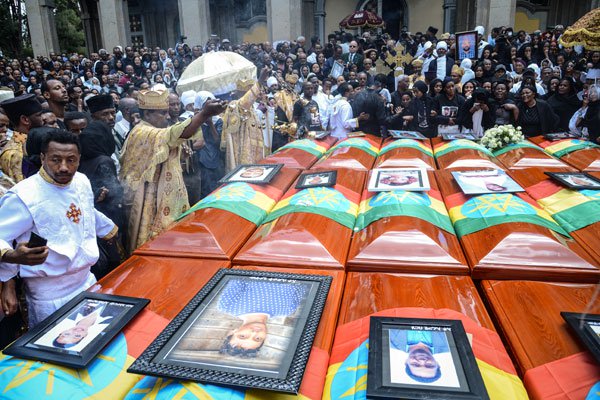 Priests hold a ceremony beside coffins of