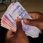 A bundle of Uganda currency held in the hands of a banker.<br />One wonders exactly what are the trading levels of the Uganda shilling. In fact many business people in Uganda are very much aware of the dominancy of the dollar all over the world. So what this article is saying is nothing more than hot air. America is determined to see to it that its domestic currency dominates all the other currencies of this planet. And our small planet is in the Milky Way galaxy and this galaxy is just one of the billions of galaxies in the universe. Within it, there are at least 100 billion stars, and on average, each star has at least one planet orbiting it. This means there are potentially thousands of planetary systems like our solar system within the galaxy! Despite all that infinite complication America wants its domestic currency to dominate. It wants its mighty imperialism and civilization realized in such complications even if it will take 100 million light years.